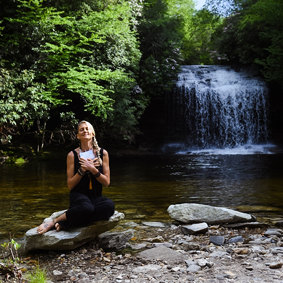 author holding book by waterfall